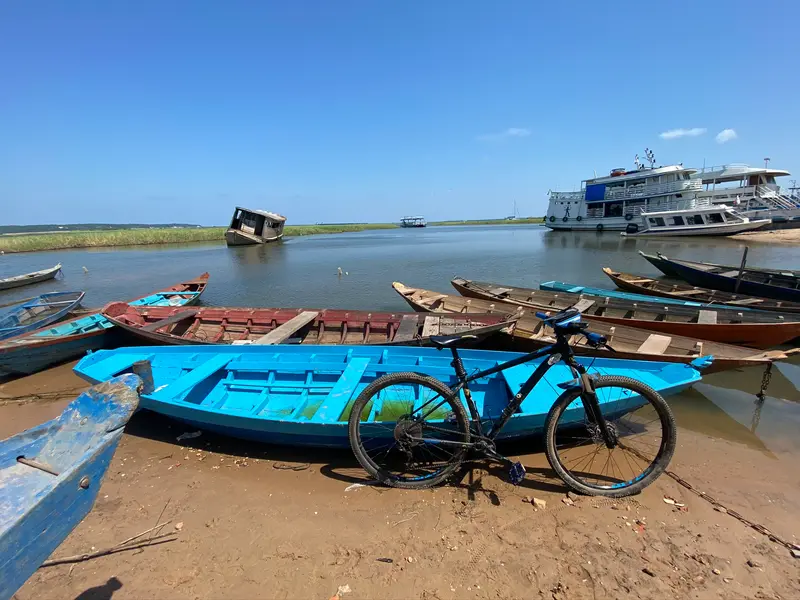 Bicicleta ao lado de canoas, com o rio ao fundo